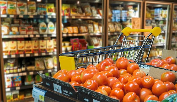 Ein Einkaufswagen steht in einem Supermarkt in der Obstabteilung.