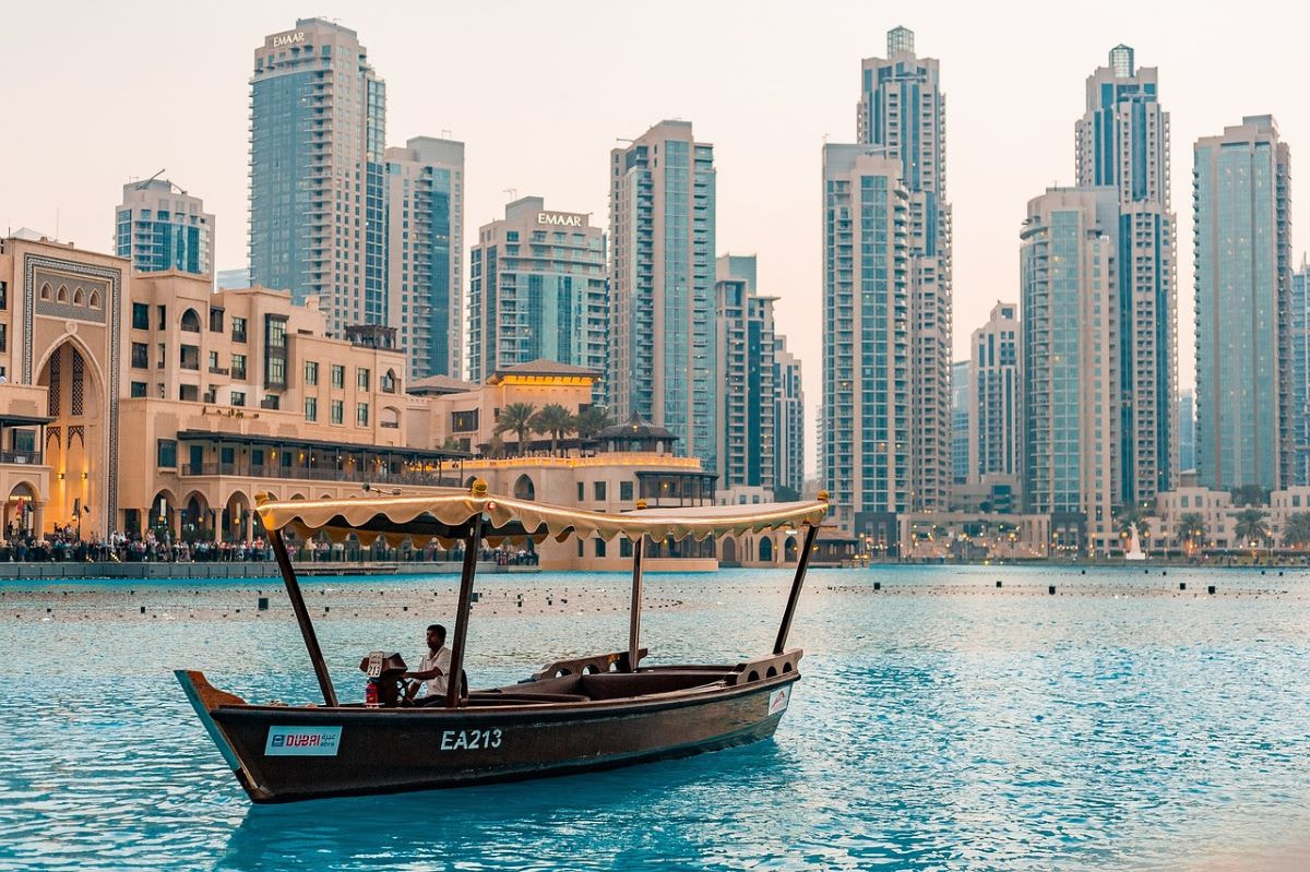 Aufnahme von Dubai mit einem Boot auf dem Wasser und Hochhäusern im Hintergrund.