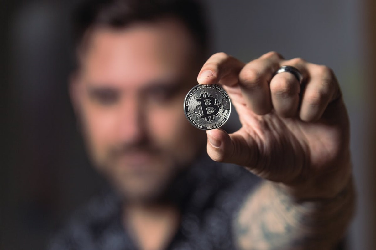 Ein Mann hält eine symbolische Bitcoin-Münze in der Hand