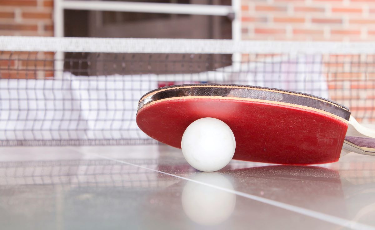 Ein Tischtennisschläger und ein Ball auf einer Tischtennisplatte